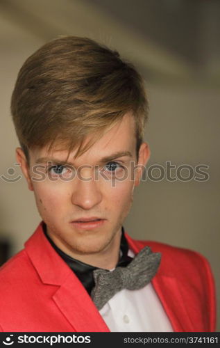 Portrait young handsome stylish man fashion model wearning bright red jacket and bow tie posing indoor