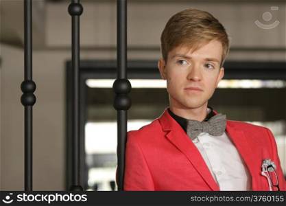 Portrait young handsome stylish man fashion model wearning bright red jacket and bow tie posing indoor