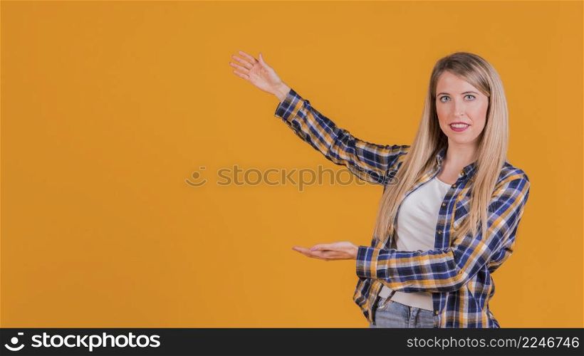 portrait young woman presenting something orange backdrop