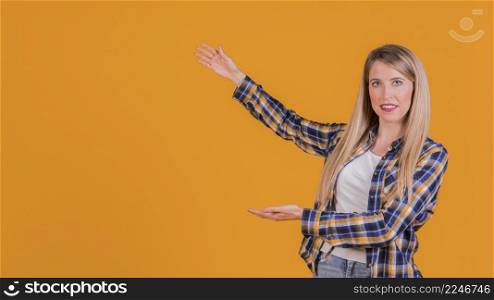 portrait young woman presenting something orange backdrop