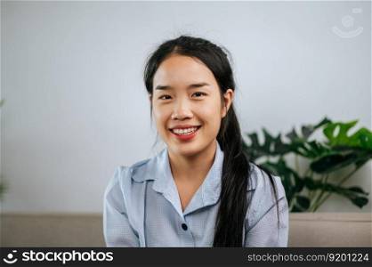 Portrait Young woman sitting on sofa in living room, She smiling with happy and looking at camera