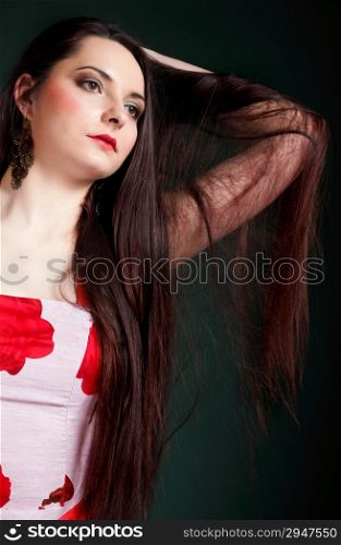 Portrait young woman straight long dark hair make up posing in studio green background
