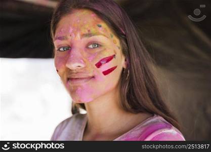 portrait young woman with face painted with holi color