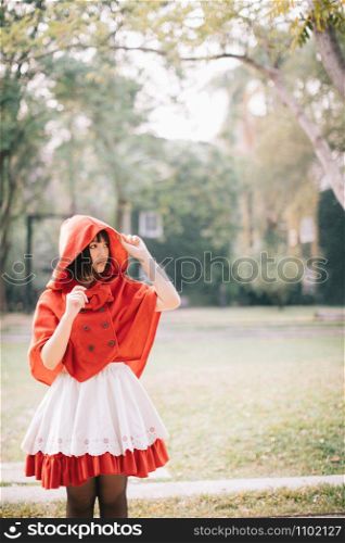 Portrait young woman with Little Red Riding Hood costume in green tree park