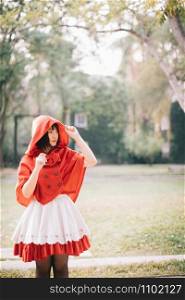Portrait young woman with Little Red Riding Hood costume in green tree park