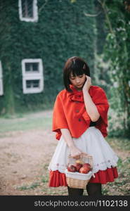 Portrait young woman with Little Red Riding Hood costume in green tree park