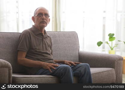 Portraits of a senior man sitting on couch at home. 