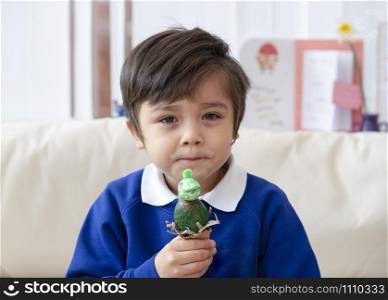 Portraot of Child boy showing his dinosaur easter eggs, Preschool kid creative making homework diy easter egg for his home work, learning by doing, Play and learn concept