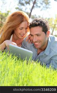 Portrat of couple laying down the grass with touchpad