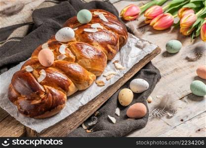 Portuguese traditional Easter cake. Folar with eggs on easter table. Blossom tulips, colorful painted eggs and feathers