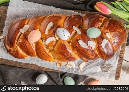Portuguese traditional Easter cake. Folar with eggs on easter table. Blossom tulips, colorful painted eggs and feathers
