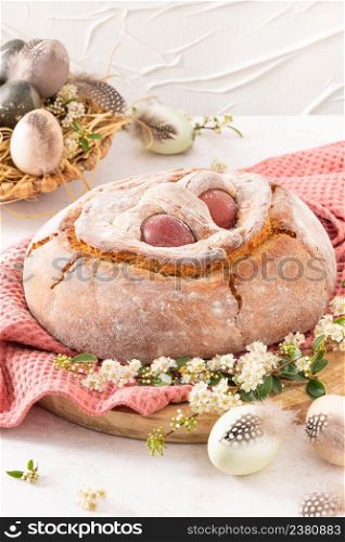 Portuguese traditional Easter cake with eggs. Typical Folar de Vale de Ilhavo, Aveiro, Portugal. Blossom flowers and colorful painted eggs decorated with feathers on easter table