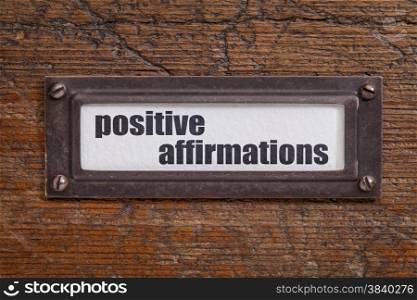 positive affirmations - file cabinet label, bronze holder against grunge and scratched wood