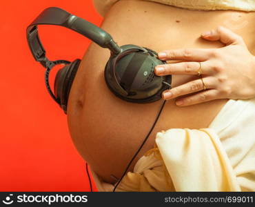 Positive aspects of baby listening to music concept. Woman with headphones on pregnant belly. Woman with headphones on pregnant belly