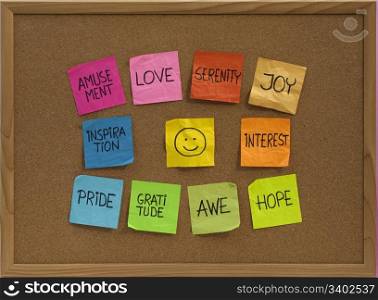 positive emotions concept - color sticky notes around smiley on cork bulletin board
