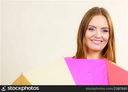 Positive face expression concept. Shy attractive smiling woman hiding behind colorful umbrella. Shy woman hiding behind colorful umbrella