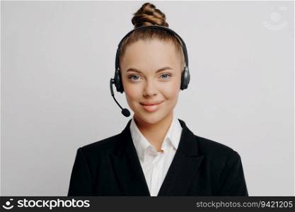 Positive female customer service rep in dark suit, with wireless headset, calmly listens to customers, smiles.
