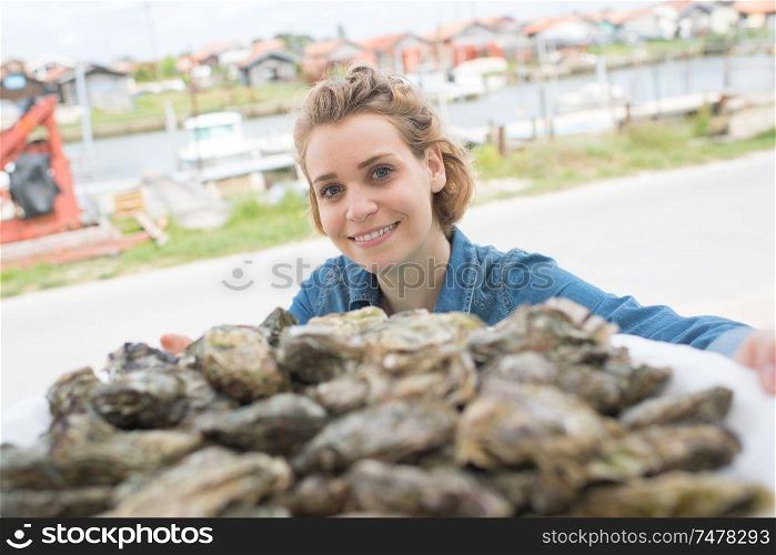 positive female seller selling fresh oysters