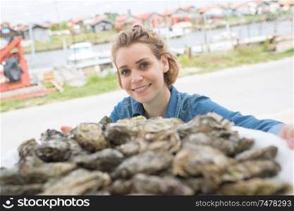 positive female seller selling fresh oysters