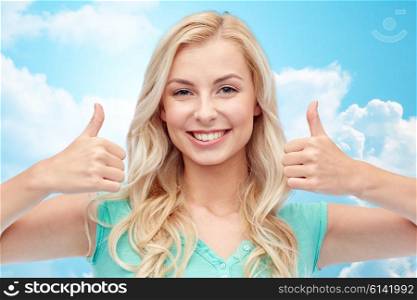 positive gesture and people concept - smiling young woman or teenage girl showing thumbs up with both hands over blue sky and clouds background. happy woman or teenage girl showing thumbs up