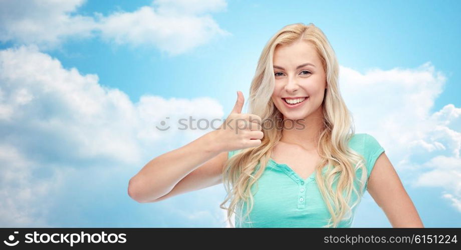 positive gesture and people concept - smiling young woman or teenage girl showing thumbs up over blue sky and clouds background. happy woman or teenage girl showing thumbs up