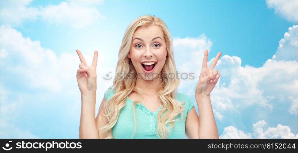 positive gesture and people concept - smiling young woman or teenage girl showing peace hand sign with both hands over blue sky and clouds background. smiling young woman or teenage girl showing peace