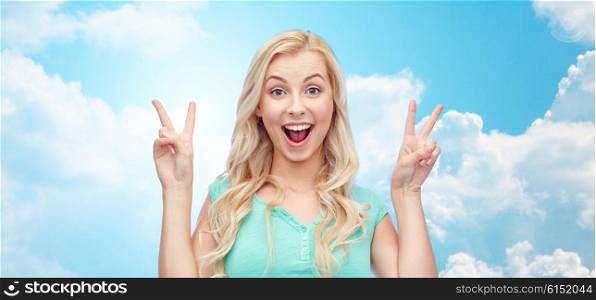 positive gesture and people concept - smiling young woman or teenage girl showing peace hand sign with both hands over blue sky and clouds background. smiling young woman or teenage girl showing peace