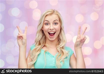 positive gesture and people concept - smiling young woman or teenage girl showing peace hand sign with both hands over pink holidays lights background. smiling young woman or teenage girl showing peace