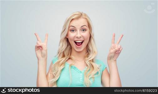 positive gesture and people concept - smiling young woman or teenage girl showing peace hand sign with both hands over gray background. smiling young woman or teenage girl showing peace