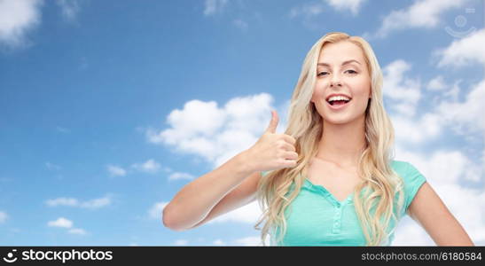 positive gesture and people concept - smiling young woman or teenage girl showing thumbs up over blue sky and clouds background. happy woman or teenage girl showing thumbs up