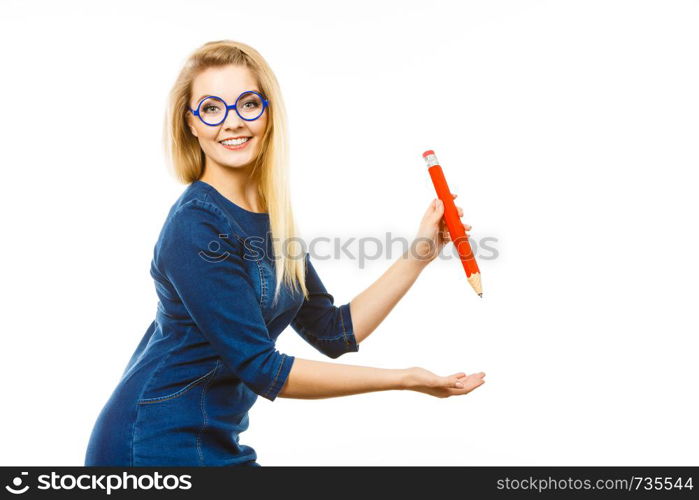 Positive smiling woman blonde student girl or female teacher holding big red pencil drawing. Studio shot on white.. Positive woman holds big pencil in hand