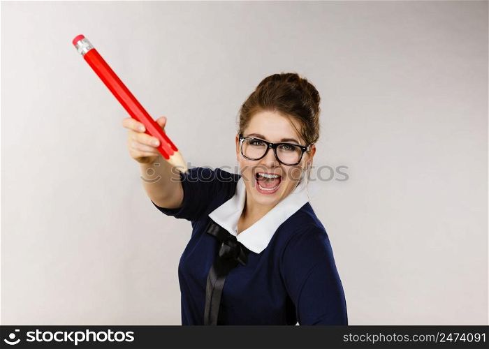 Positive smiling woman student girl or female teacher holding big red pencil drawing. Studio shot on grey. Smiling woman holds big pencil in hand