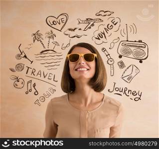 Positive smiling woman wearing sunglasses planning her vacation. Sketches of her plans of trip around her