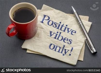 Positive vibes only - handwriting on a napkin with cup of coffee against gray slate stone background