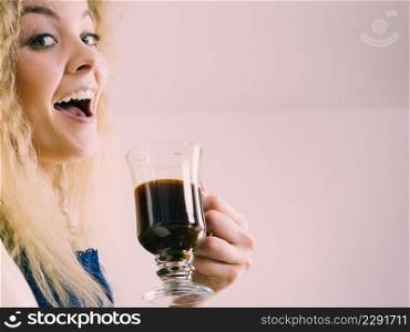 Positive woman holding black coffee about to drink. Getting morning energy, hurry up before going to work.. Positive woman drinking her morning coffee