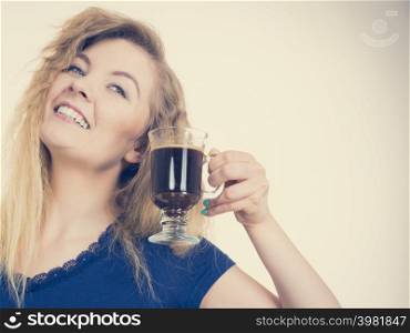 Positive woman holding black coffee about to drink. Getting morning energy, hurry up before going to work.. Positive woman drinking her morning coffee