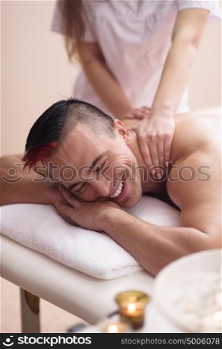 Positive young man having a back massage in a spa center