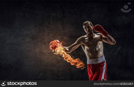 Possessing power and endurance. Strong boxer man in gloves against cement wall