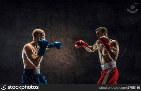 Possessing power and endurance. Two strong boxer men in gloves against cement wall