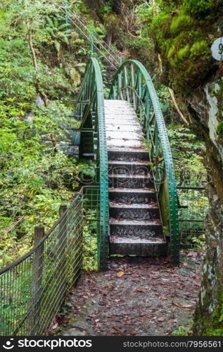 Possibly pre-fabricated metal footbridge in woodland.