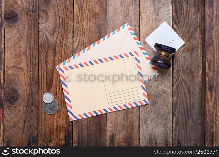 Post card with envelope and old stamp with coins on grunge wooden table still life