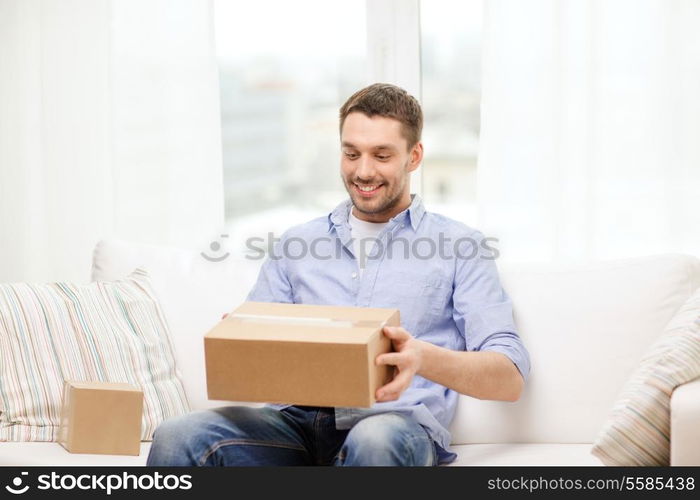 post, home and lifestyle concept - smiling man with cardboard boxes at home