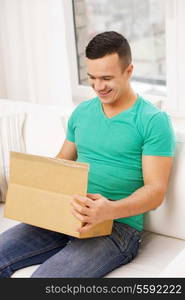 post, home and lifestyle concept - smiling man with cardboard boxes at home