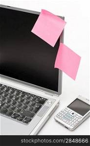 Post-it stickers on business laptop and phone isolated on white