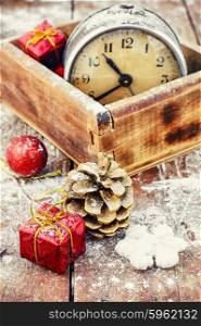 Postcard Christmas time. Stylish wooden box with clock on the background of pine cones and Christmas decorations