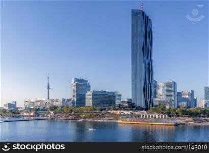 Postcard cityscape with modern buildings and the tallest skyscraper in Austria, on the Danube river shore, in the district of Donau City of Vienna.