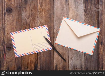 Postcard with fountain pen end envelope on old wooden table