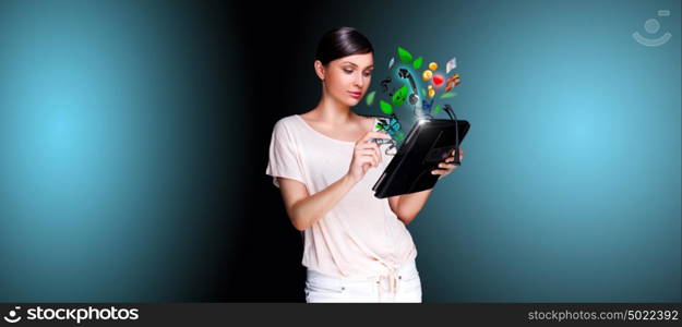 Poster portrait of young beautiful woman holding her universal device - tablet pc. Lots of things are appearing from the display. Universality of modern devices concept