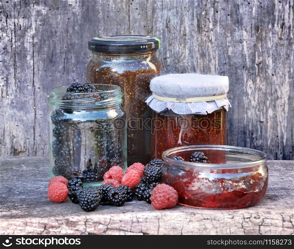 pot of jam with red fruits on wooden background