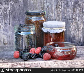 pot of jam with red fruits on wooden background